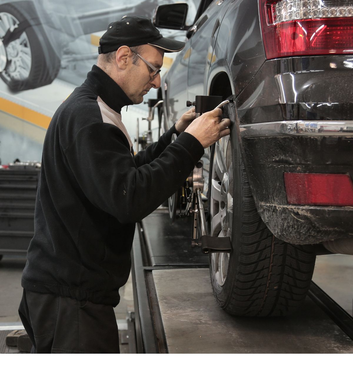 Technician performing wheel alignment on an SUV in a professional service bay